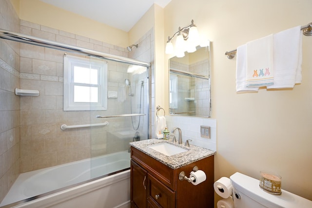 bathroom with vanity, toilet, and combined bath / shower with glass door