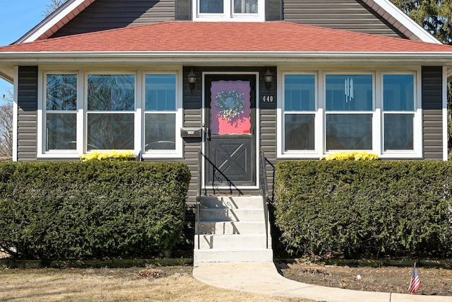 doorway to property with roof with shingles