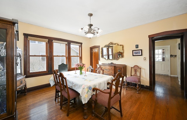 dining room with a chandelier, baseboards, and dark wood-style flooring