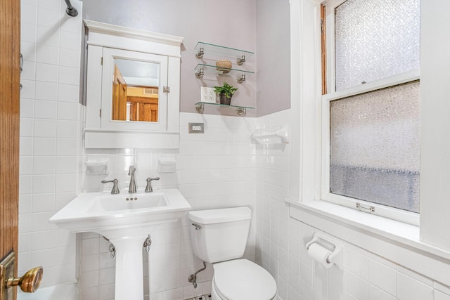 bathroom with toilet and tile walls