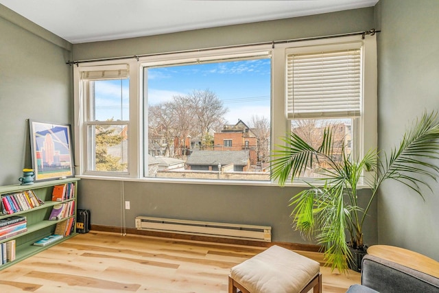 sitting room with a baseboard heating unit and wood finished floors