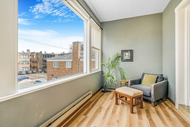 sitting room featuring light wood-style floors, a baseboard radiator, and baseboards