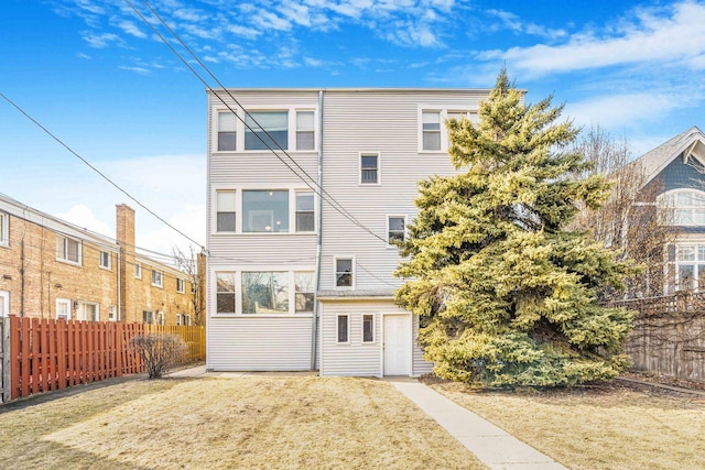 rear view of house with fence and a yard