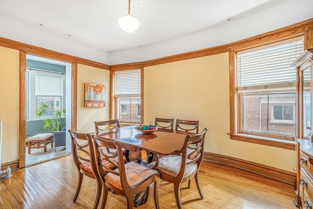 dining space featuring light wood finished floors and baseboards