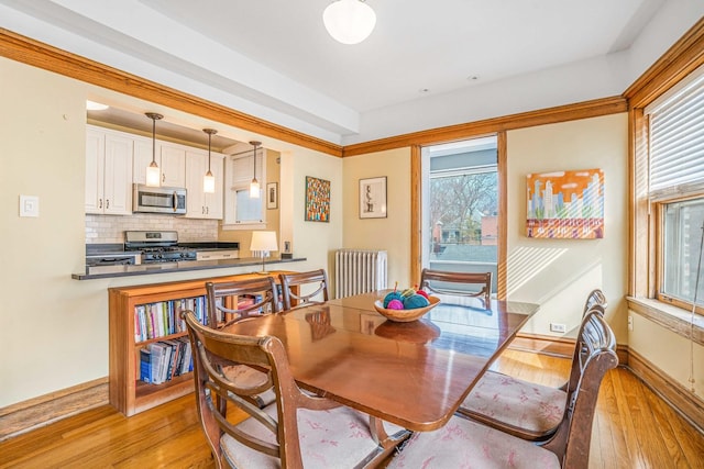 dining room featuring light wood finished floors, a healthy amount of sunlight, and radiator