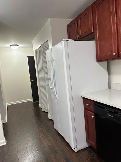 kitchen with black dishwasher, dark wood-style flooring, white refrigerator with ice dispenser, light countertops, and baseboards