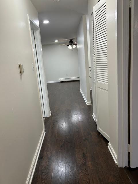 hall with baseboards, a baseboard heating unit, and dark wood-type flooring