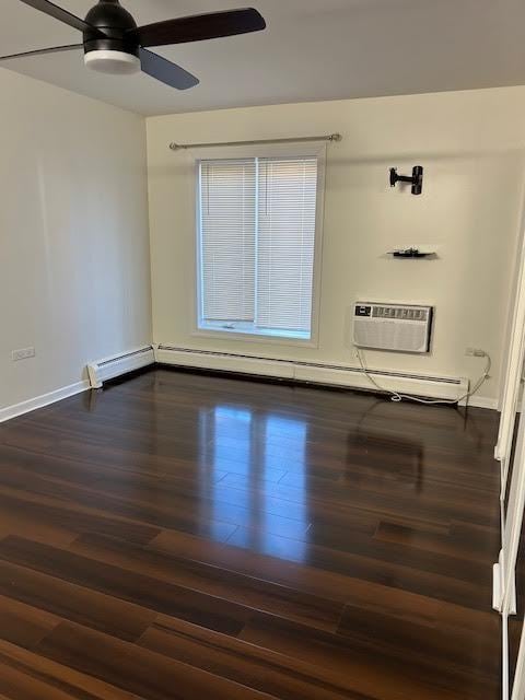 spare room featuring ceiling fan, a wall unit AC, a baseboard heating unit, baseboards, and dark wood finished floors