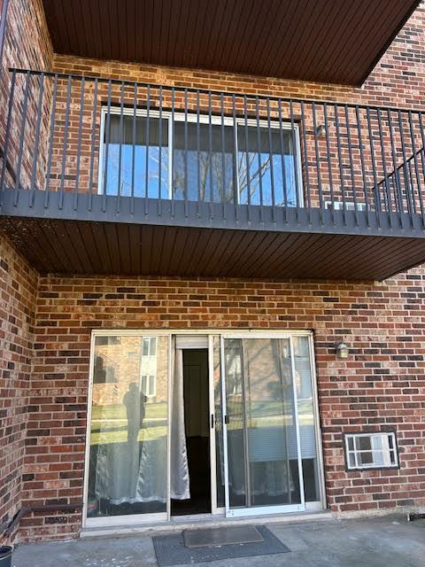 exterior space featuring a balcony and brick siding