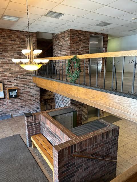 bar featuring brick wall, a drop ceiling, visible vents, and tile patterned floors