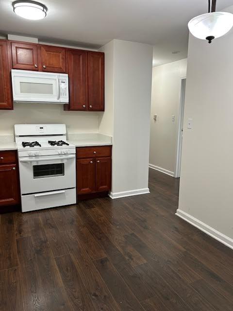 kitchen featuring white appliances, baseboards, light countertops, and dark wood-type flooring