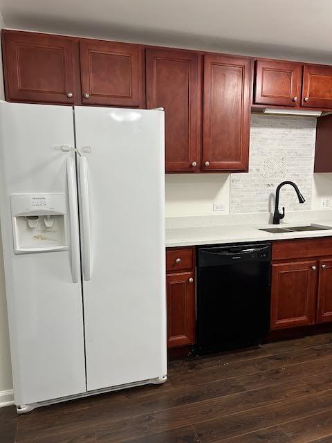 kitchen featuring dark wood-type flooring, a sink, black dishwasher, light countertops, and white fridge with ice dispenser