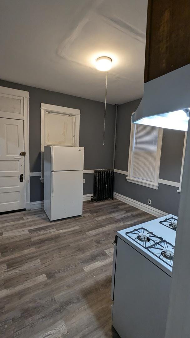 kitchen with white appliances, radiator heating unit, baseboards, and dark wood-style flooring