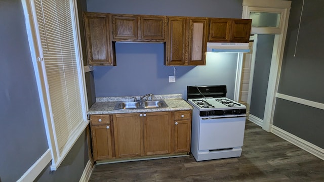 kitchen featuring white gas stove, light countertops, dark wood-type flooring, a sink, and under cabinet range hood