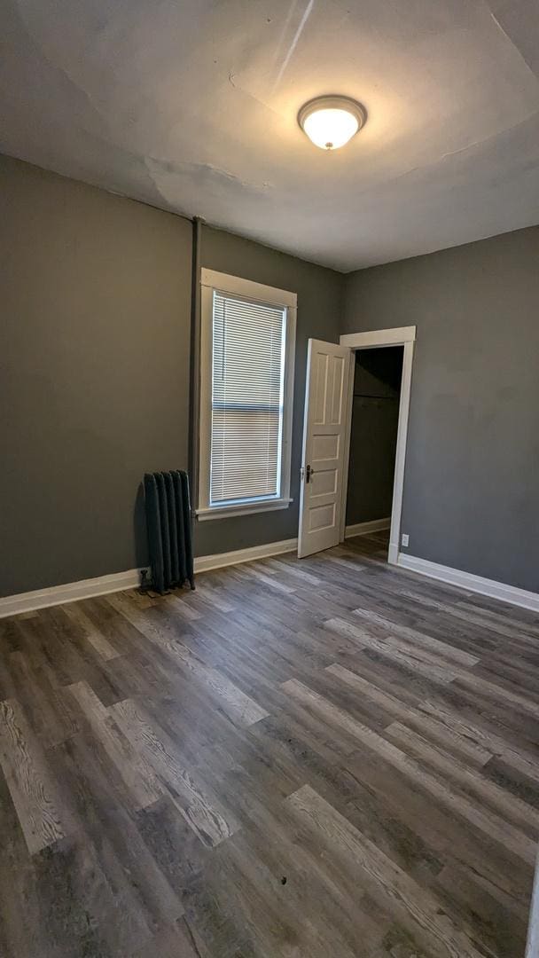 empty room with dark wood-style flooring and baseboards