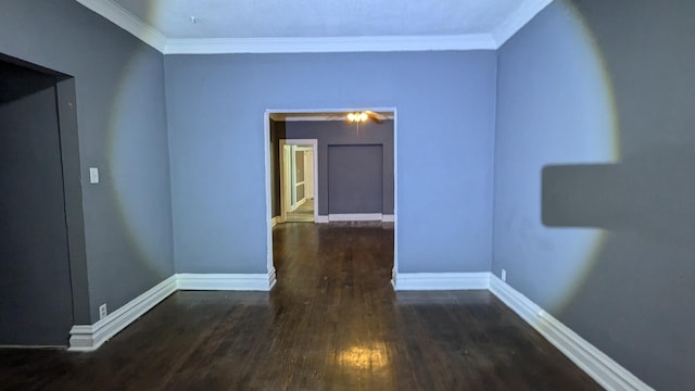 empty room featuring baseboards, wood finished floors, and crown molding