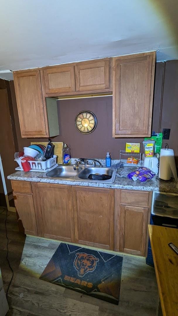 kitchen with light countertops, wood finished floors, and a sink