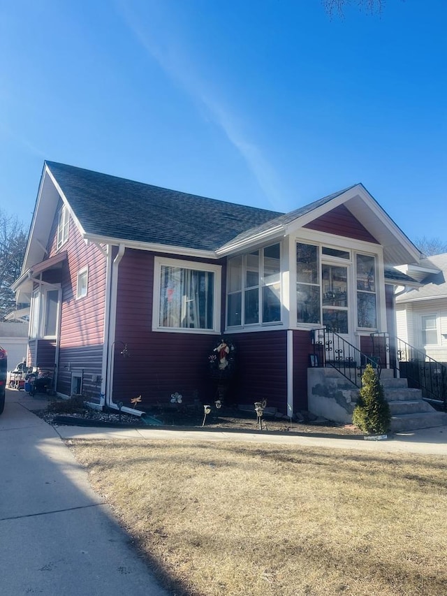 view of front of house with a front yard and a shingled roof