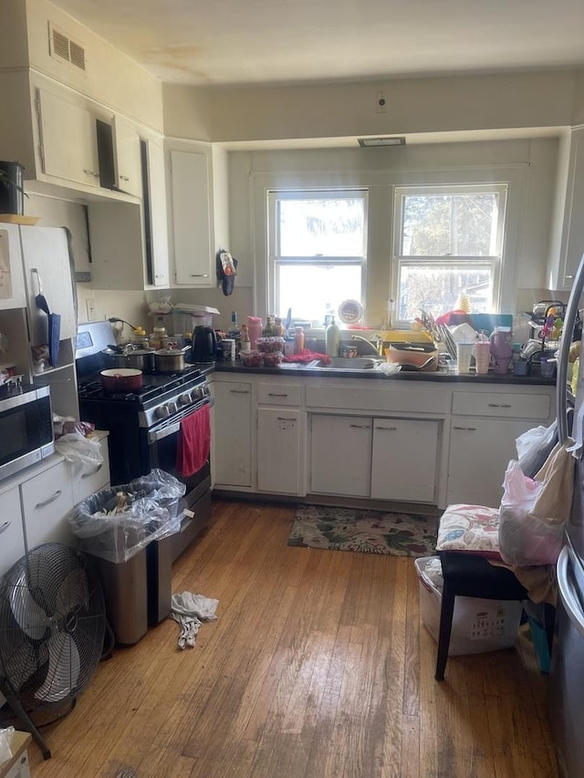 kitchen featuring stainless steel appliances, plenty of natural light, visible vents, and hardwood / wood-style floors