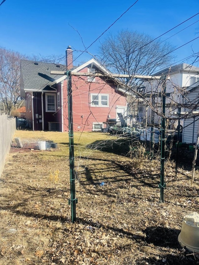 back of house featuring a chimney and fence