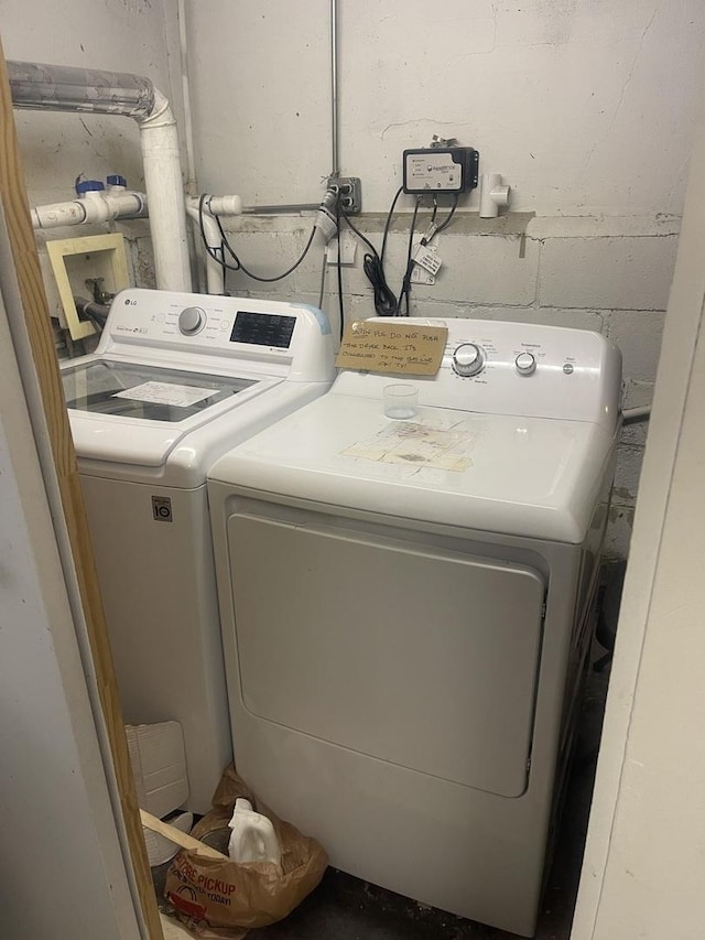 laundry area featuring washer and clothes dryer and concrete block wall