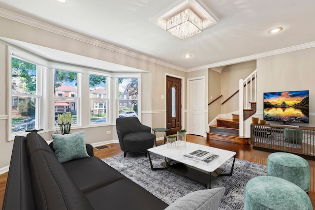 living room with stairway, wood finished floors, visible vents, and crown molding