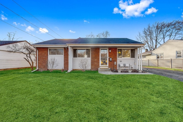 ranch-style home featuring brick siding, driveway, a front yard, and fence