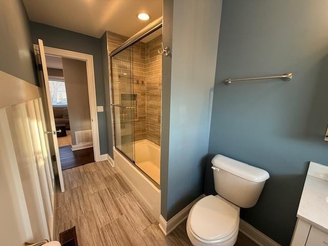 full bathroom with baseboards, toilet, wood finished floors, and vanity