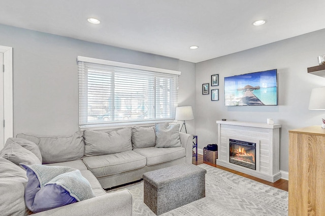 living room with a glass covered fireplace, baseboards, wood finished floors, and recessed lighting