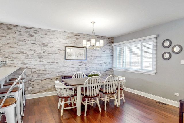 dining space featuring dark wood finished floors, visible vents, an accent wall, and baseboards