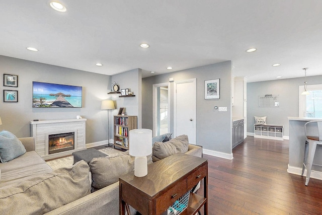 living room with dark wood-style floors, a glass covered fireplace, recessed lighting, and baseboards