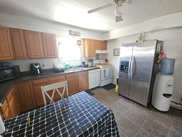 kitchen with white appliances, dark countertops, ceiling fan, under cabinet range hood, and a sink