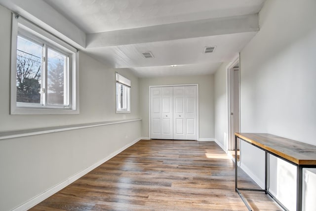 unfurnished bedroom with visible vents, a closet, baseboards, and wood finished floors