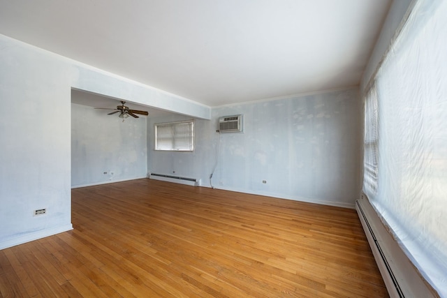 empty room featuring a baseboard radiator, an AC wall unit, ceiling fan, and light wood finished floors