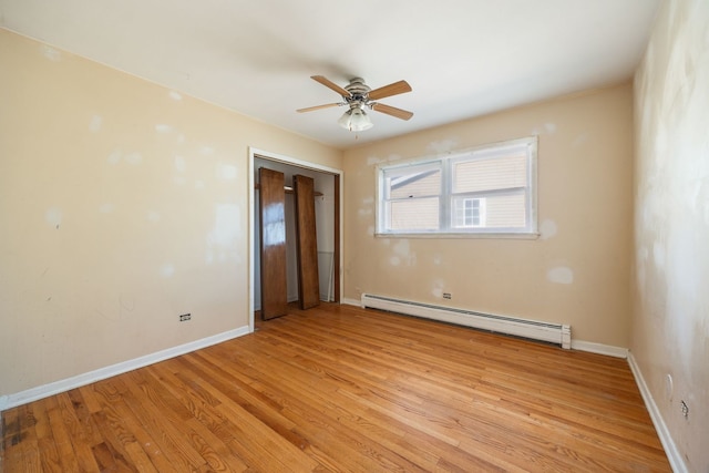 empty room featuring a ceiling fan, a baseboard radiator, baseboards, and light wood finished floors