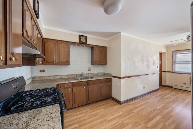 kitchen with light wood-style flooring, a baseboard heating unit, black range with gas cooktop, a sink, and under cabinet range hood