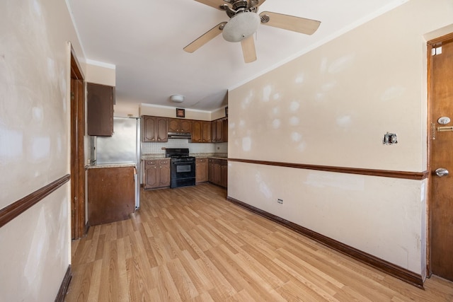 kitchen with light wood-style flooring, light countertops, ornamental molding, black range with gas stovetop, and backsplash