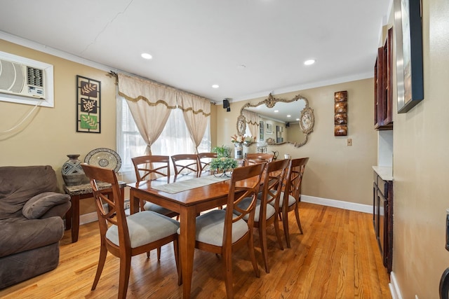 dining room featuring light wood finished floors, an AC wall unit, ornamental molding, and baseboards