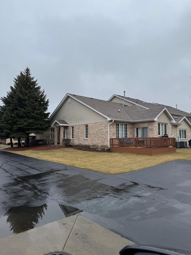 view of front of property with brick siding, a deck, and a front lawn