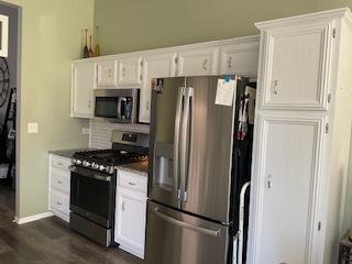 kitchen with white cabinets, dark countertops, stainless steel appliances, and dark wood-style flooring