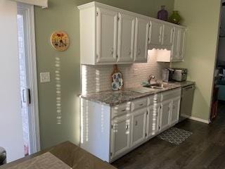 kitchen with dark wood-style floors, white cabinets, backsplash, and stainless steel dishwasher