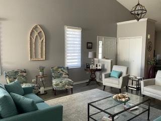 living room featuring baseboards, a notable chandelier, high vaulted ceiling, and wood finished floors