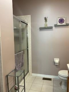 full bath featuring toilet, a shower stall, baseboards, and tile patterned floors