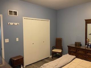 bedroom featuring a closet, visible vents, and wood finished floors