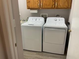 laundry area featuring light wood finished floors, washing machine and clothes dryer, and cabinet space