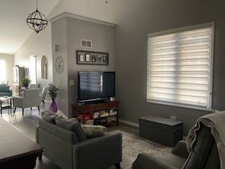 living area with visible vents, a chandelier, and vaulted ceiling