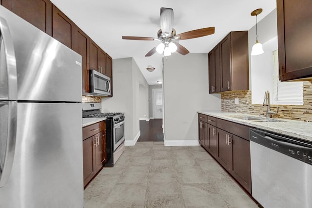 kitchen with light stone counters, stainless steel appliances, a sink, baseboards, and tasteful backsplash