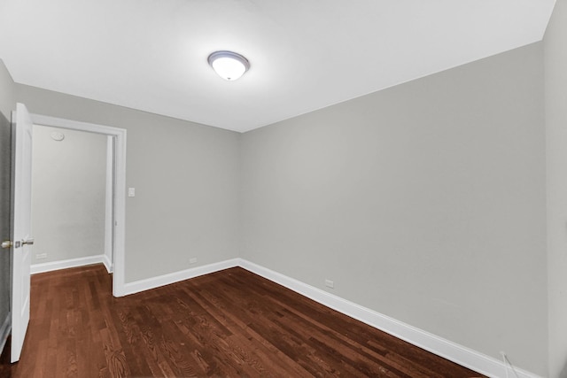 spare room featuring baseboards and dark wood finished floors