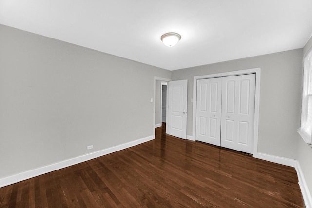 unfurnished bedroom featuring a closet, wood finished floors, and baseboards