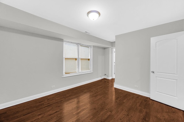 spare room with baseboards and wood finished floors